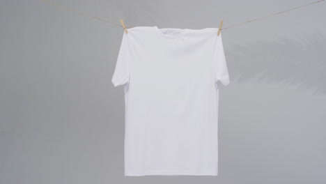 video de camiseta blanca con clavijas de ropa y espacio de copia en fondo gris