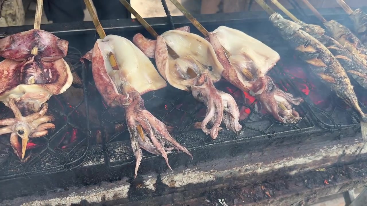 Calamari e pesce freschi che grigliano su un barbecue a carbone
