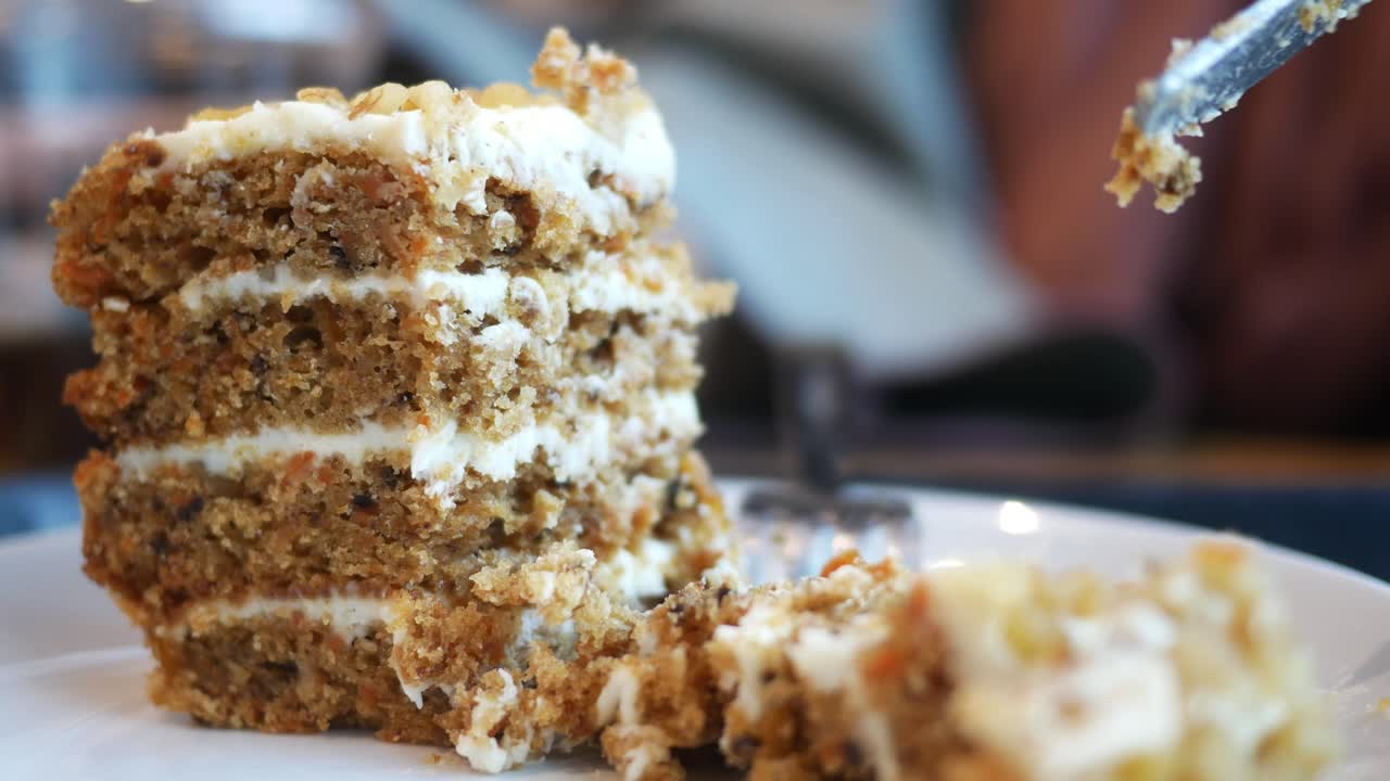 disparo en primer plano de una rebanada de pastel de zanahoria siendo cortada con un cuchillo