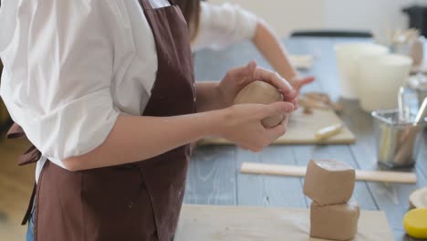 the girl crushes the clay in the hands. potter's work close-up. female hands crumple clay closeup. no face woman crushes the clay in the hands