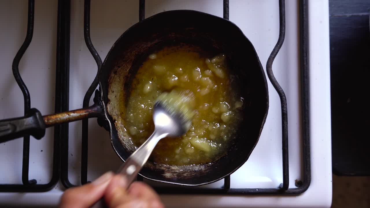 Chef making homemade caramel sauce, mixing butter and sugar over hot stove