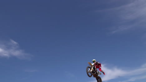 un piloto de motocross atrapa un gran aire, volando sobre la cámara desde un salto de tierra