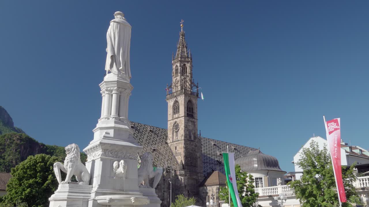 Back view of the Walther von der Vogelweide Monument on Waltherplatz and the cathedral in the background in Bozen - Bolzano, South Tyrol, Italy