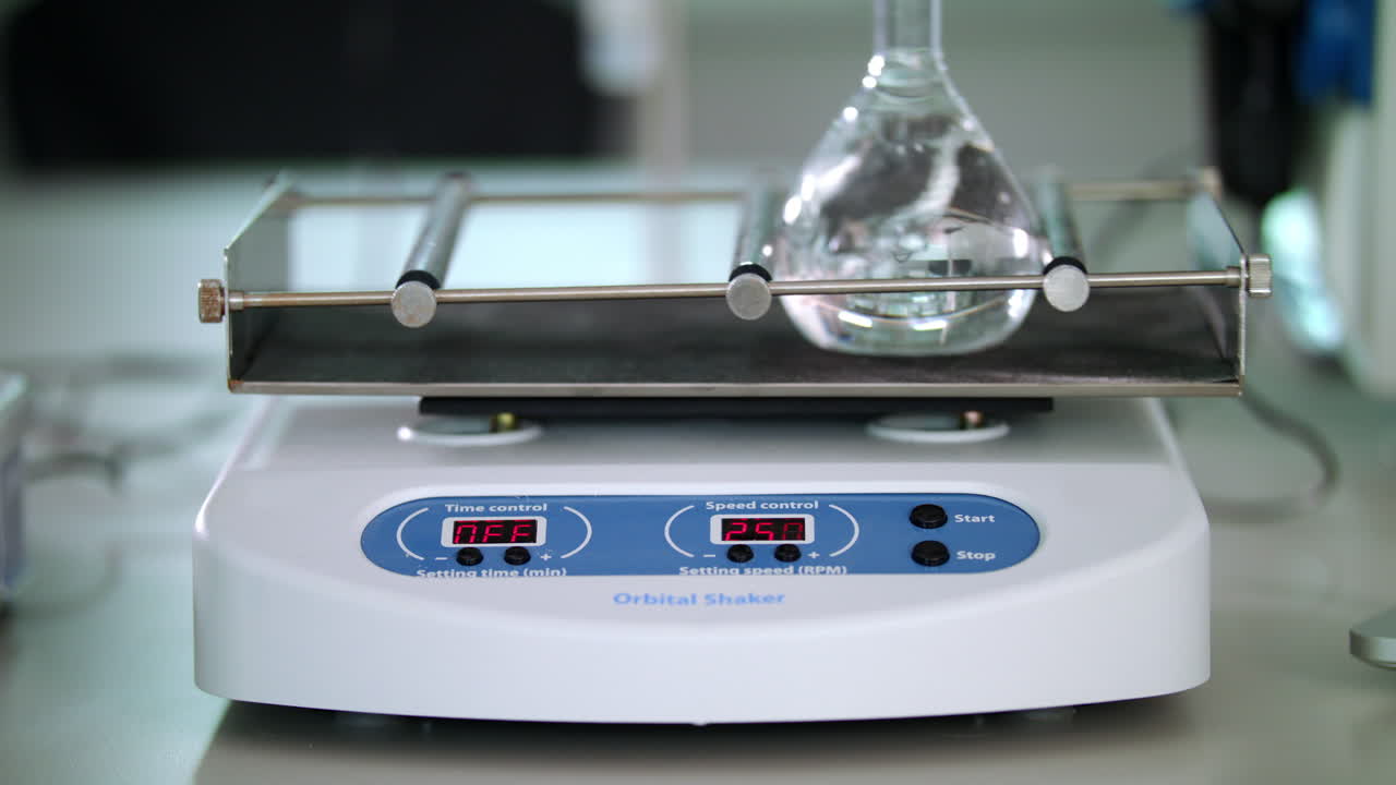 Shaker flasks is working. Laboratory equipment. Mixing liquid in glass flask