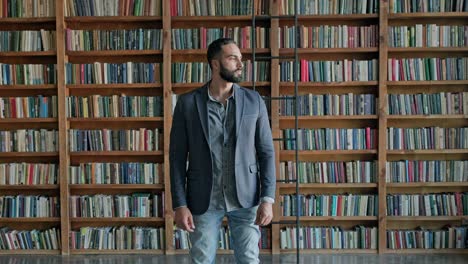 un tipo está de pie en la biblioteca. una morena atractiva con barba de oriente medio.