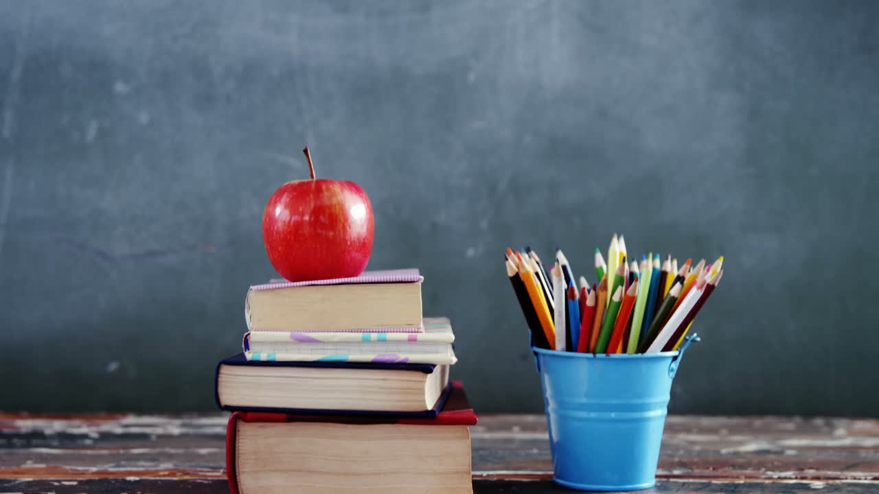 manzana en la pila de libros con lápiz de color en la mesa