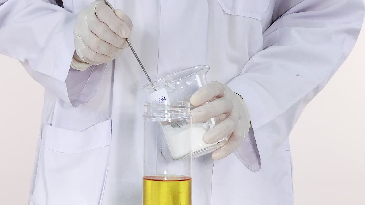A scientist stirs and mixes liquids in clear beakers, showcasing a hands-on laboratory process.