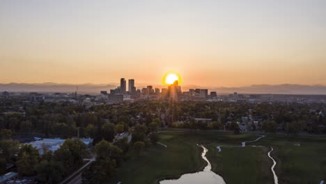 Timelapse-Aéreo-Sobre-El-Parque-De-La-Ciudad-En-Denver,-Colorado-Con-La-Puesta-De-Sol-Detrás-De-Los-Rascacielos-Del-Centro