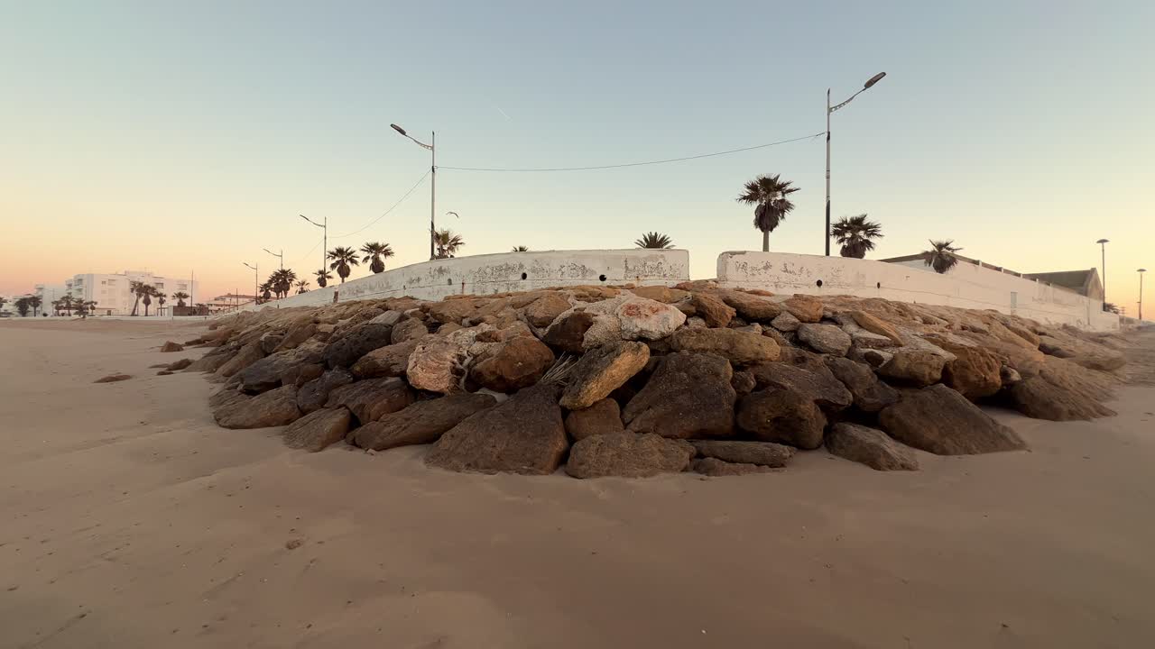 Avvicinamento a una barriera rocciosa costruita sulla spiaggia sabbiosa per proteggere dall'erosione.
