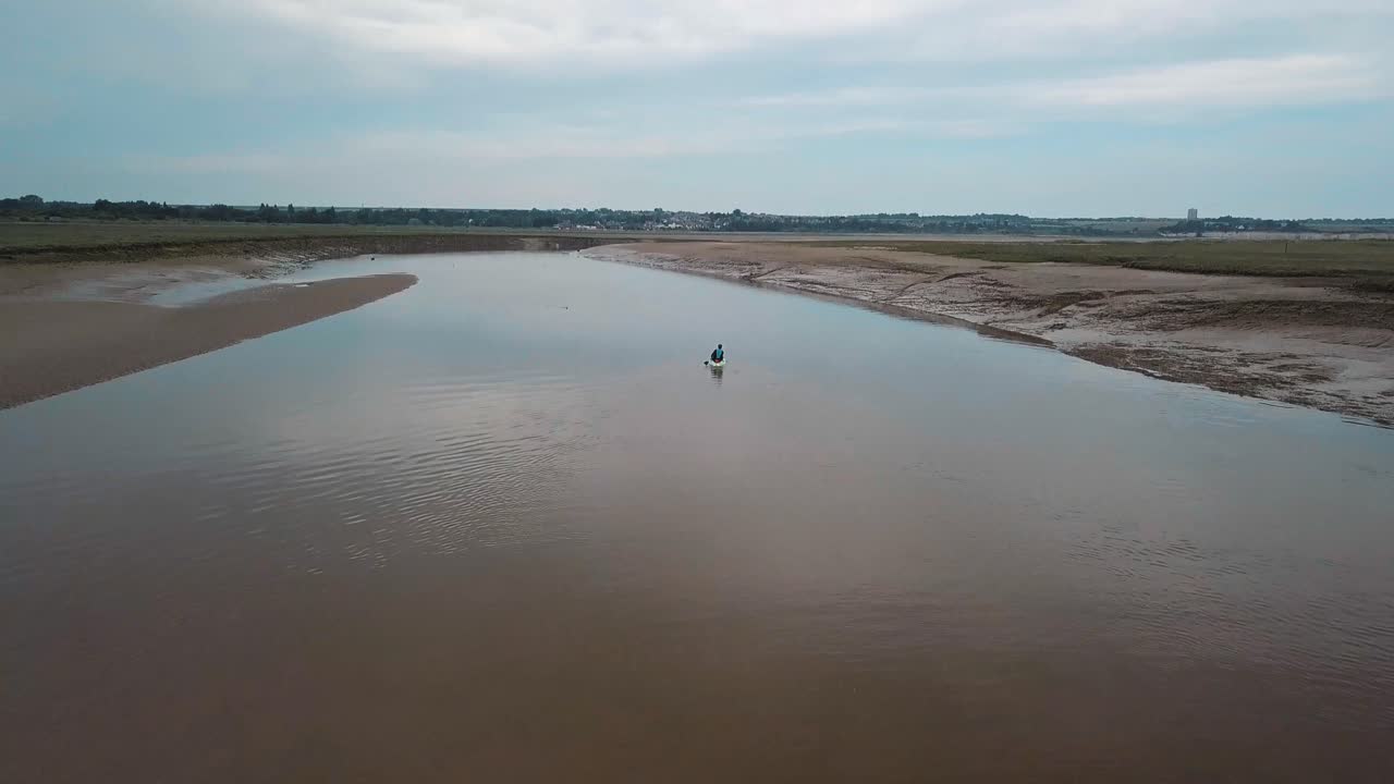 구불구불한 강에서 카약을 타는 남자, 배경에 아름다운 풍경을 드러내기 위해 드론 팬