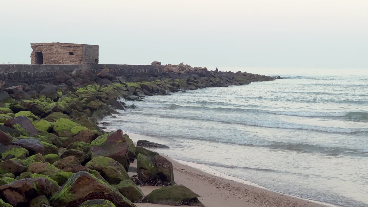 Static view of the sea lapping against a walkway among the rocks. Daylight