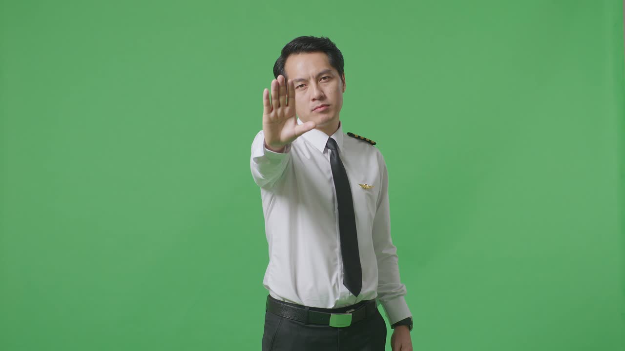 Asian Man Pilot Looking At Camera And Disapproving With No Hand Sign In The Green Screen Background Studio