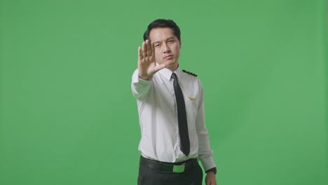 asian man pilot looking at camera and disapproving with no hand sign in the green screen background studio