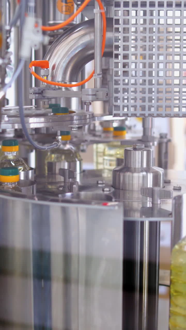 Bottling line of sunflower oil. Bottles with vegetable oil against the background of factory equipment Vertical video