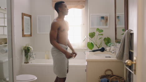 happy african american man dancing shirtless in bathroom looking in mirror having fun morning routine getting ready enjoying positive self image doing silly dance celebrating success