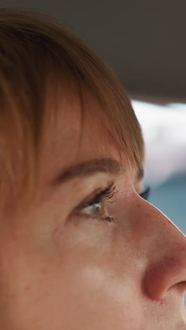 impatient young woman waits sitting in car in traffic jam on hot day. driver blows face with mouth suffering from heat on blurred background close side view