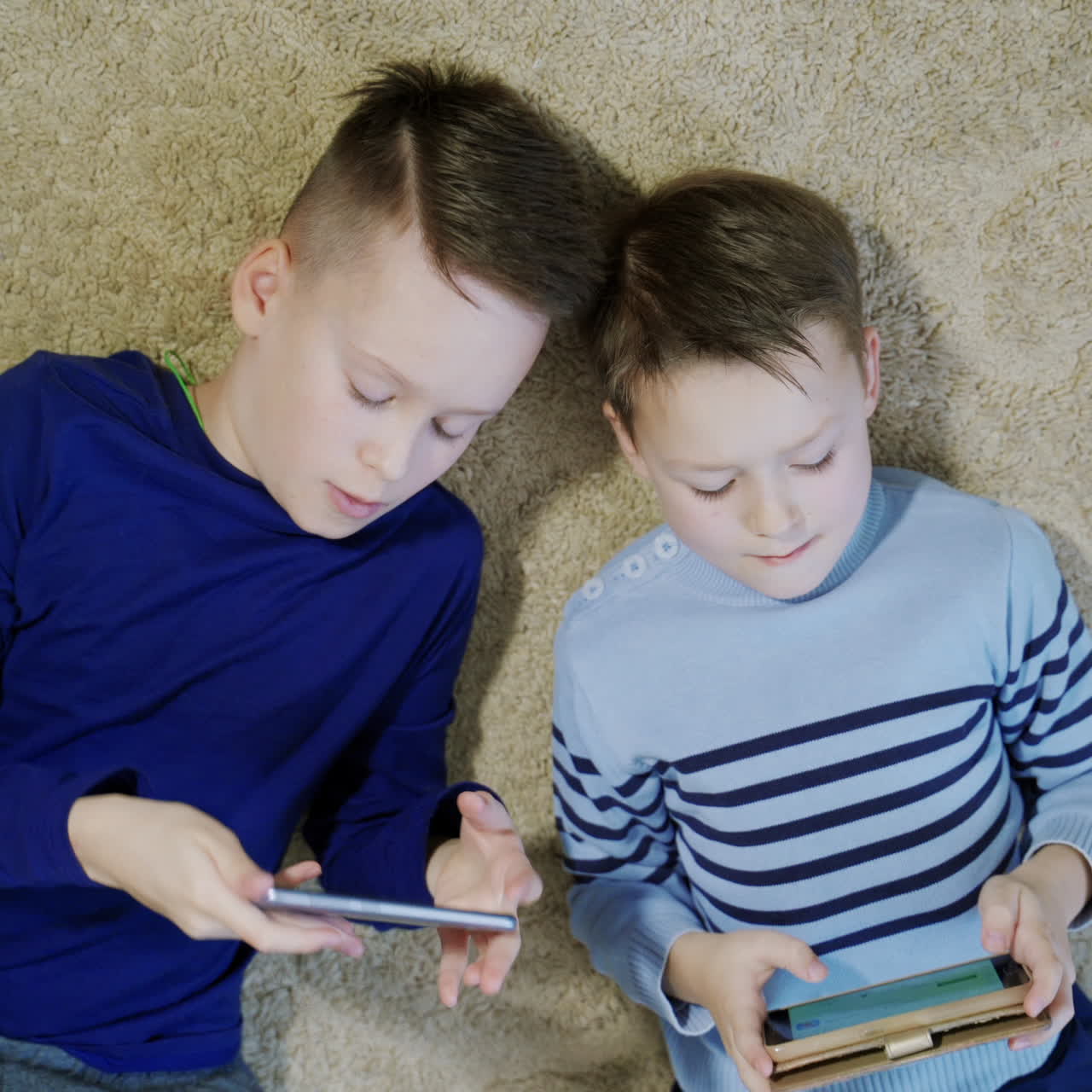 Little boys playing game on mobile together. Child playing video game at home