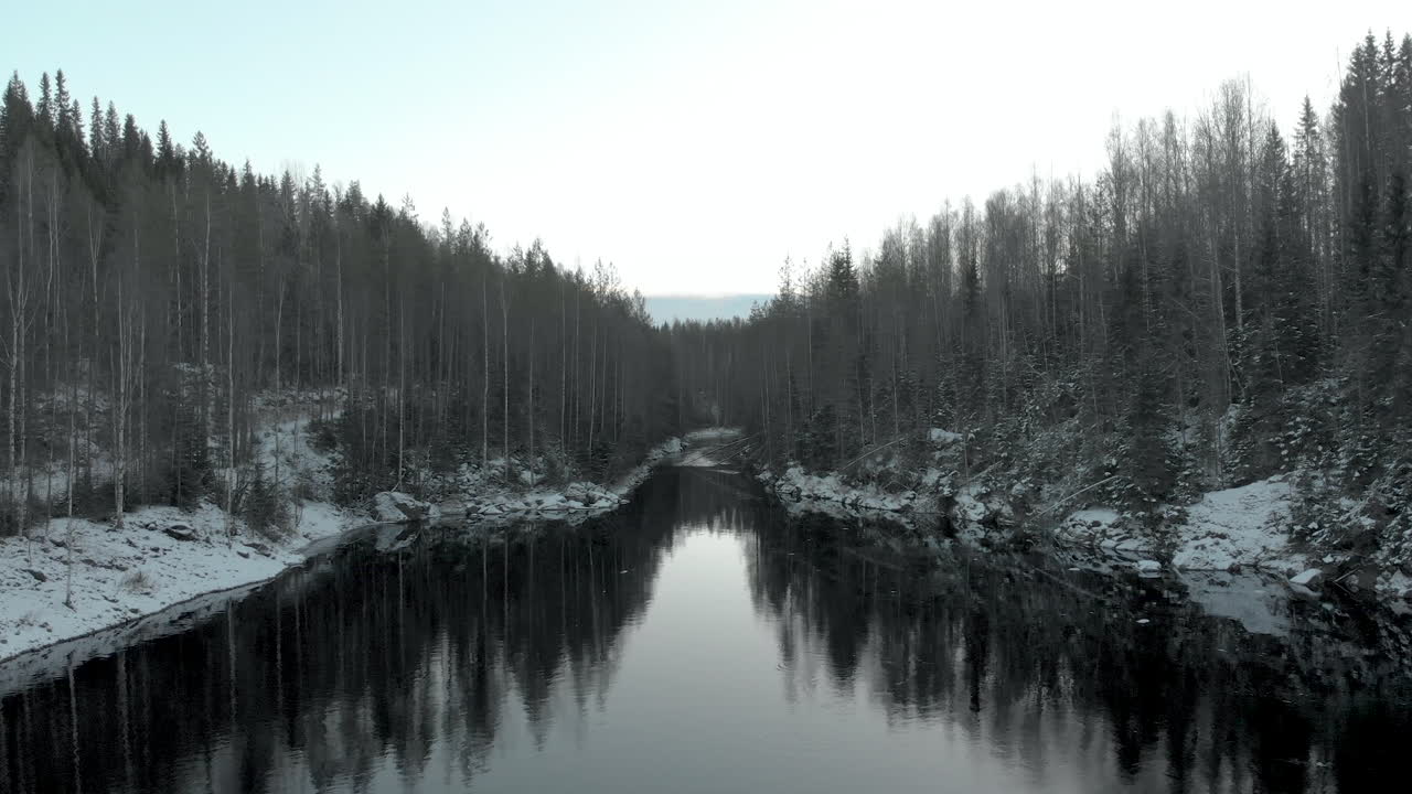 Luftfoto, droneoptagelse, flyver over en flod, mod en bladløs skov, med den første sne på jorden, nær Joensuu, Nordkarelen, Finland.