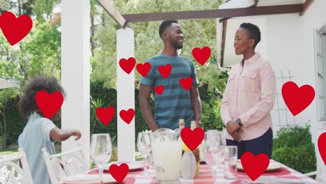 Animation-of-hearts-over-happy-african-american-family-preparing-meal-in-garden