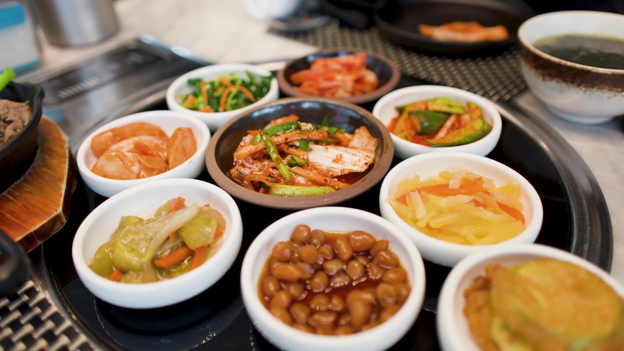 Pengambilan gambar jarak dekat berbagai lauk Korea termasuk kimchi dan sayuran fermentasi di atas meja.
