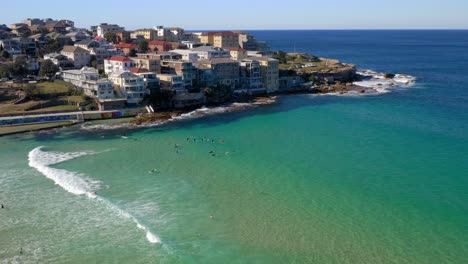 waterfront buildings in ben buckler point with tourist swimming and surfing in bright blue sea