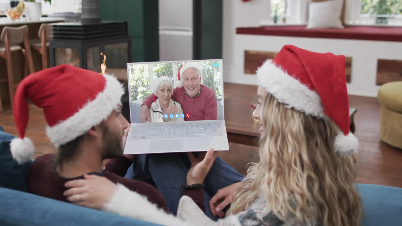 feliz pareja caucásica y padres ancianos teniendo navidad llamada de video portátil, cámara lenta
