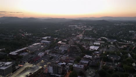 charlottesville city at dusk. american downtown in virginia state during golden sunset. silhouette of mountain range in background. drone top down shot.