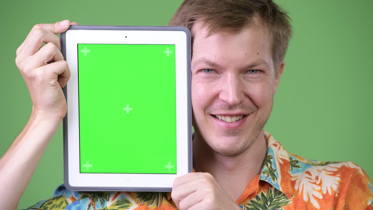 Young happy handsome tourist man showing digital tablet