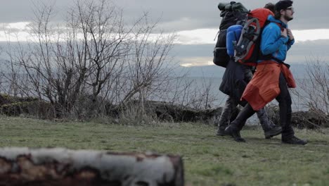 two males backpackers walk on hiking path by coast