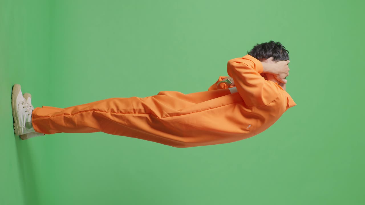 persona en mono naranja posando contra un fondo verde