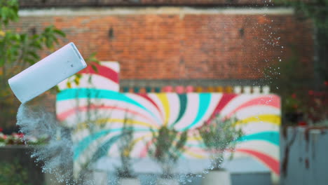 glass of milk suspended in the air as it spills in motion against a wall with flowers, adding color to the surroundings