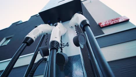 refueling process of an electric car. a shot under the hatch where the electric eco car charges. the electric car charging hatch opens automatically. a male hand inserts an erectile car