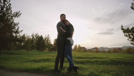 una pareja abrazándose en un parque al atardecer