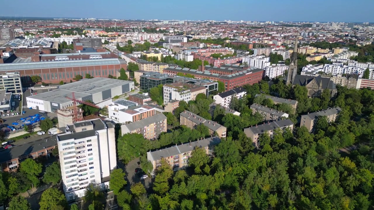 Ponte ferroviario arrugginito che passa sopra i binari del treno in un contesto urbano lussureggiante e verde a Berlino, Germania, infrastruttura di trasporto. Magnifica panoramica aerea ripresa da drone.