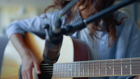 woman fingers strumming strings of guitar