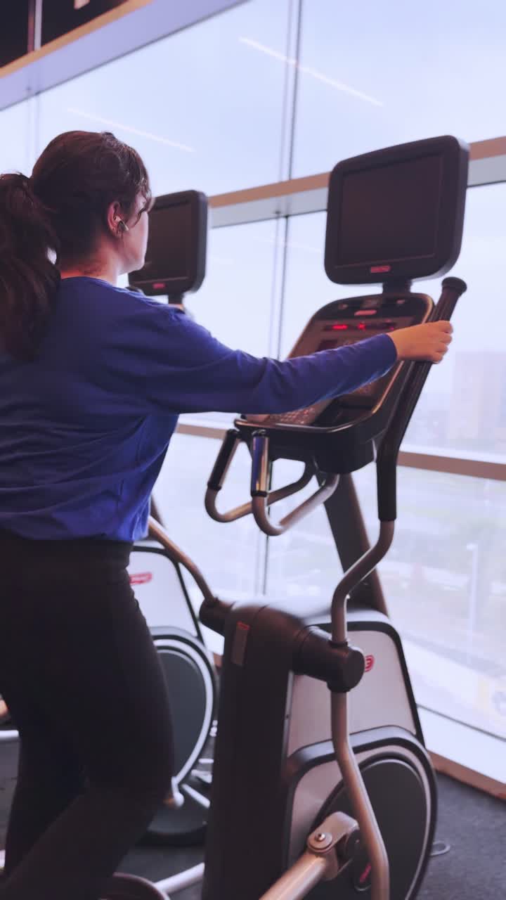 A woman is on a stationary bike in a gym