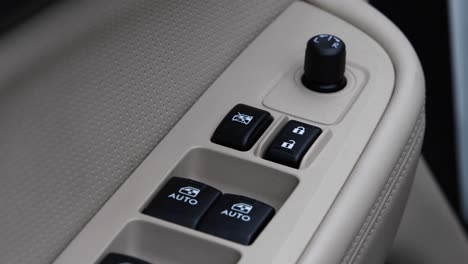 Shot-of-the-interior-of-an-automobile-showing-off-the-window-switch-and-mirror-controls,-black-switches-with-a-white-leather-contrast