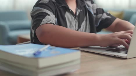 close up teenage boy use laptop computer at table in living room