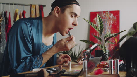 glamorous transgender man applying lipstick at home