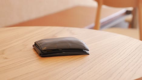 black leather wallet on a wooden table in a cafe