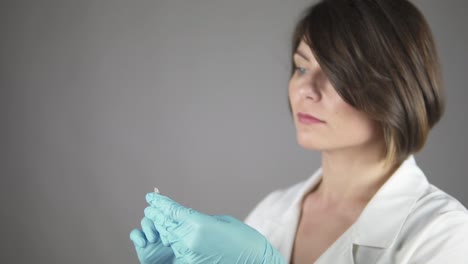 médico femenino preparando cuidadosamente y inyección aislada en fondo gris. enfoque en las manos. concepto de atención médica y medicina