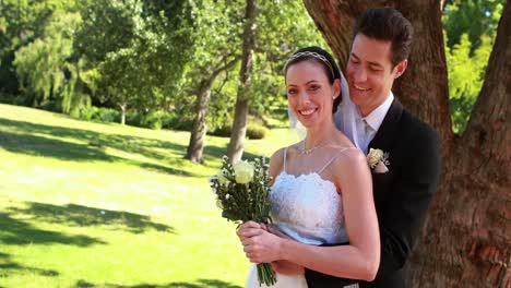 happy newlyweds smiling at camera and embracing