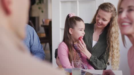 video de una madre caucásica feliz limpiando la cara de su hija en la mesa de la cena familiar