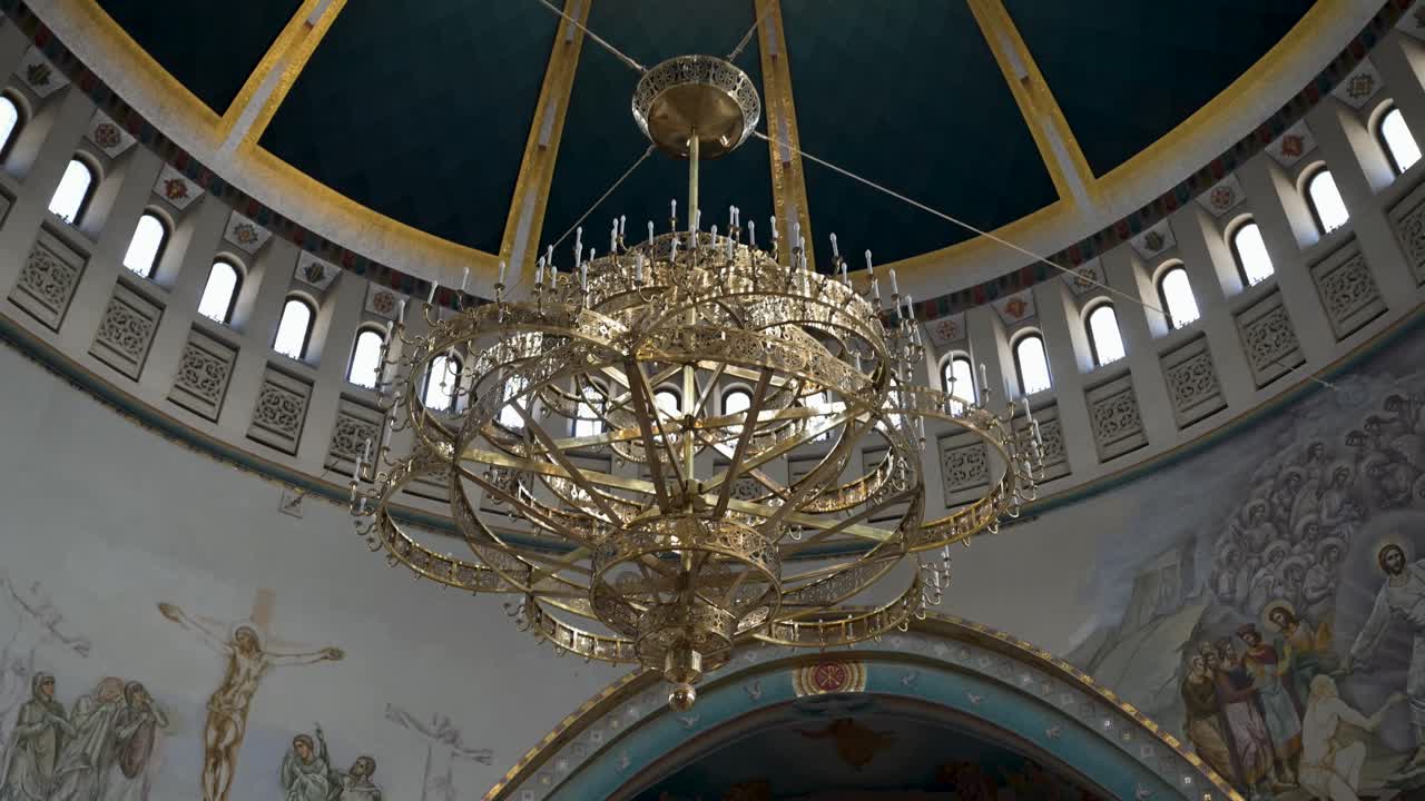 Lampadari in bronzo elaborati e luce naturale dalle finestre a cupola illuminano i mosaici dorati e l'interno architettonico moderno della Cattedrale della Resurrezione di Cristo.