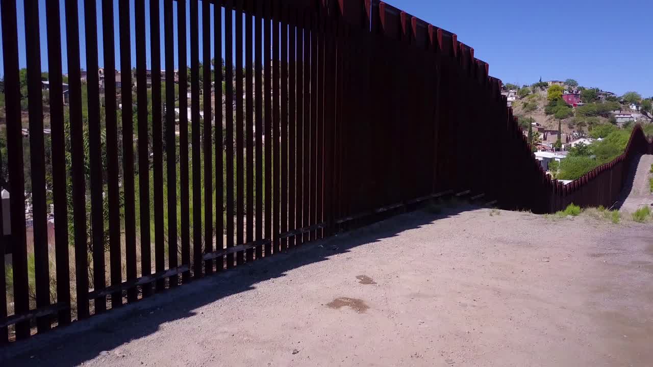 antena de lento ascenso a lo largo de la cerca del muro fronterizo mexicano-estadounidense que revela la ciudad de nogales