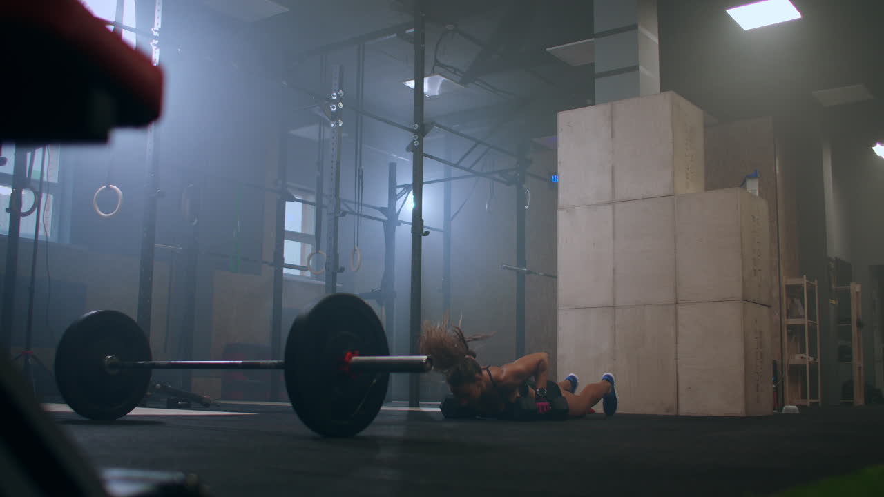 strong woman during workout workout keeps burpee with heavy dumbbells doing push UPS and jumping out in the gym