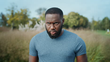 Man-making-grimaces-on-camera-in-park.-Handsome-sportsman-standing-outdoors