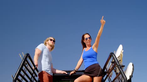 Man-and-woman-with-sand-boards-looking-at-a-distance-4k