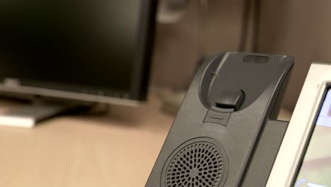 un primer plano de una mano levantando y golpeando un teléfono de oficina contra la base del teléfono en un cubículo de oficina en cámara lenta