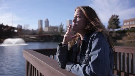 tired, homeless woman taking a drag on her cigarette in wide angle